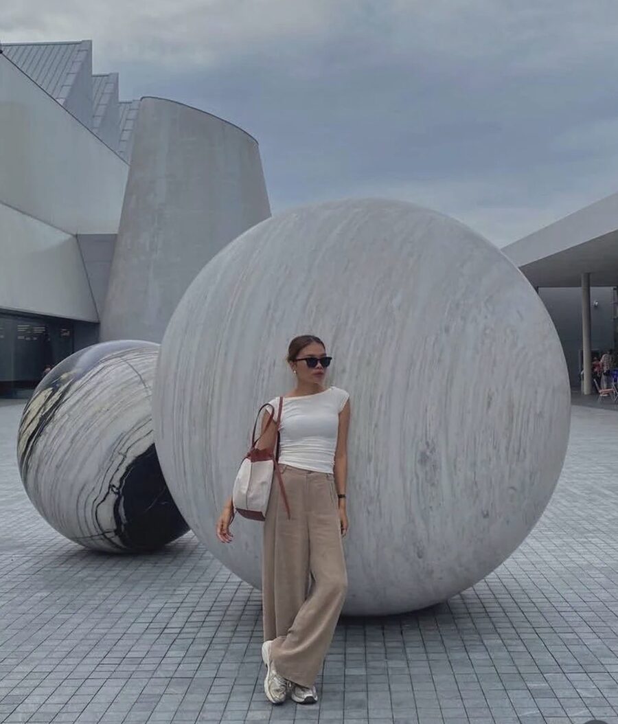 Inney in dark sunglasses leaning against a giant stone sphere