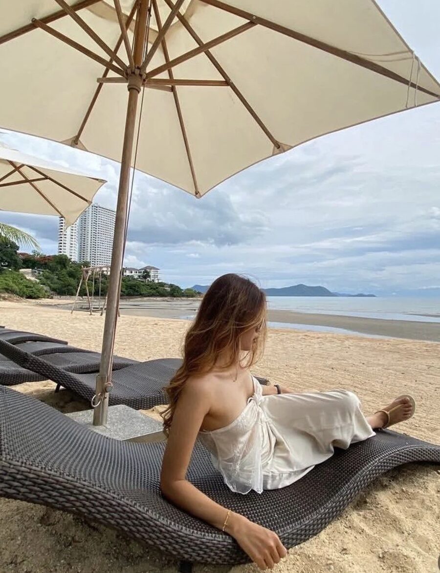 Inney reclining on a beach lounger under an umbrella, looking away